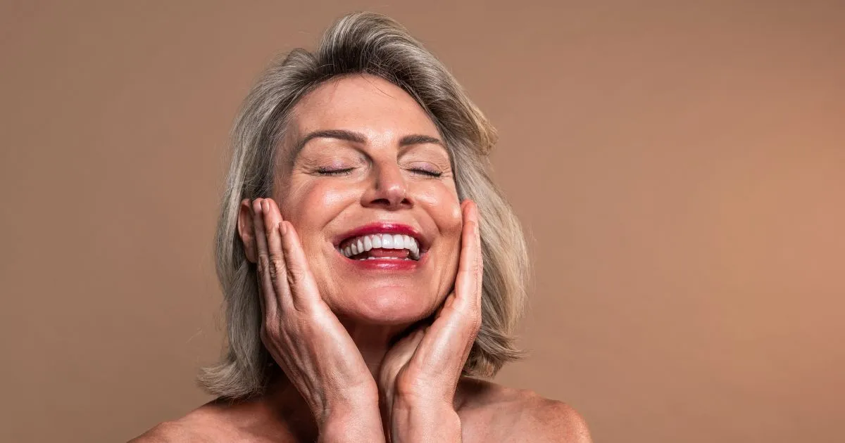 Middle-aged woman smiling, hands on cheeks, showing teeth bonding in Annapolis, MD